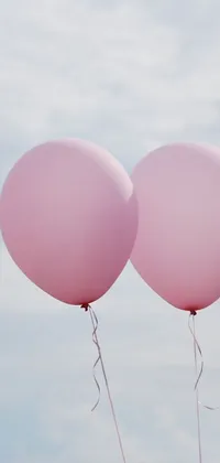 Decorate your phone's background with this charming live wallpaper featuring two pink balloons gracefully floating in a pale sky