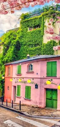 This lovely phone live wallpaper showcases a charming pink building surrounded by lush greenery and flowers on the side of a road