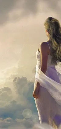 This phone live wallpaper showcases a stunning woman in a white ensemble standing atop a towering mountain, overlooking panoramic views of soft clouds and gentle waves