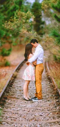 This phone live wallpaper depicts a serene scene of a couple situated on a train track nestled among beautiful woods
