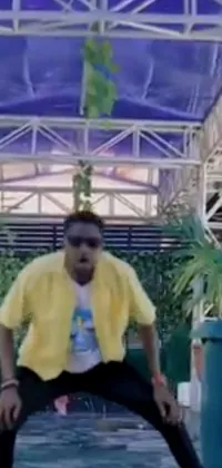 This dynamic phone live wallpaper features a man sporting a yellow shirt and black pants, seemingly caught in the midst of an exhilarating music video
