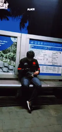 This phone live wallpaper showcases a man engrossed in his cell phone while sitting on a bench at a bustling bus station