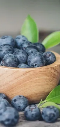 Elevate your phone's home screen with a charming live wallpaper featuring a wooden bowl filled with luscious blueberries