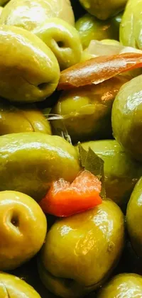 Looking for a unique and eye-catching live wallpaper for your phone? Look no further than this one featuring a pile of green olives adorned with a single carrot