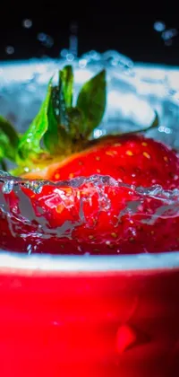This live wallpaper showcases a stunning macro photograph of a ripe, red strawberry resting in a water-filled bowl