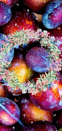 This phone live wallpaper features a colorful and vibrant digital rendering of plums with sprinkles, surrounded by a laurel wreath on a beautiful galaxy background