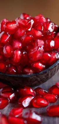 This live phone wallpaper displays a bowl of vibrant pomegranate seeds surrounded by colorful jellybeans