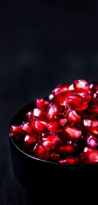 Enhance your phone screen with this exquisite live wallpaper that depicts a delicious bowl of pomegranate seeds showcased on a wooden table