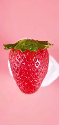 This phone live wallpaper features a realistic depiction of a strawberry on a napkin, with a touch of surrealism