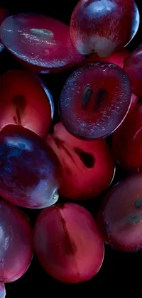 This live wallpaper features a vibrant macro photograph of a pile of plums, sitting on top of a table