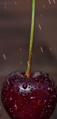 This phone live wallpaper features a mesmerizing close-up of a juicy cherry placed on a wooden table