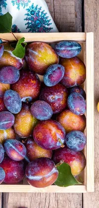 Decorate your phone screen with the beauty of nature and local foods with this live wallpaper! This vibrant wallpaper features a box of plums sitting on a wooden table and surrounded by warm sunlight