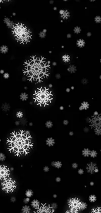 Looking for a beautiful and mesmerizing live wallpaper for your phone? Look no further than this stunning black and white photo of snow flakes gently falling against a dark Christmas night sky
