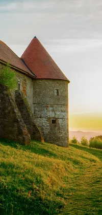 This live phone wallpaper showcases a beautiful romanesque-style stone building situated atop a lush green hill in Slovakia