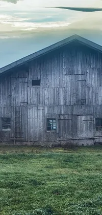 This phone live wallpaper depicts a scenic barn that rests on a lush green field