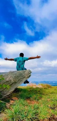 Enjoy a stunning phone live wallpaper of a man sitting on a rock amidst a beautiful natural landscape