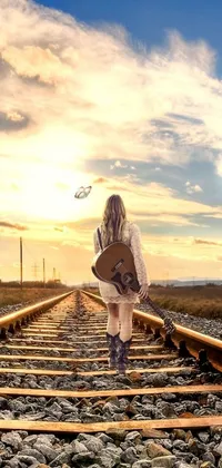 This live phone wallpaper features a picturesque scene of a person holding a guitar standing on train tracks