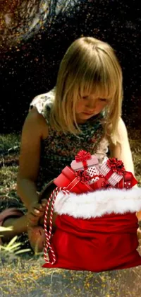 This delightful live wallpaper depicts a young girl happily kneeling with a bag and surrounded by classic Christmas imagery