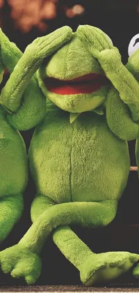 Get a cute and fun phone live wallpaper with three green stuffed animals sitting next to each other