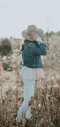 This stunning phone live wallpaper captures a beautiful petite woman in a field wearing a denim jacket and a white dress