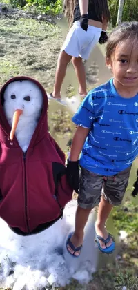 This phone live wallpaper depicts a heartwarming winter scene featuring two kids standing beside a snowman