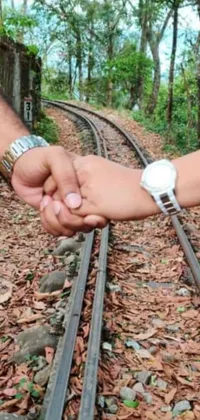 This Assamese-inspired live phone wallpaper showcases a romantic image of a couple walking hand in hand on train tracks against a scenic natural backdrop