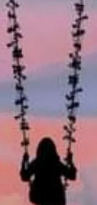 This phone live wallpaper features a silhouette of a person on a swing at sunset, framed against a colorful, gradient sky