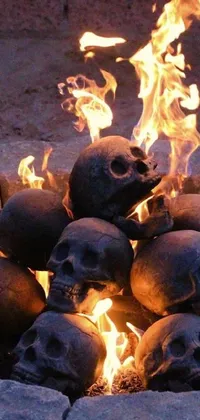 This phone live wallpaper depicts a pile of skulls on fire