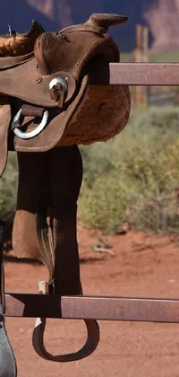 This live wallpaper for your phone features a true-to-life depiction of a saddle resting on a fence in Monument Valley, USA