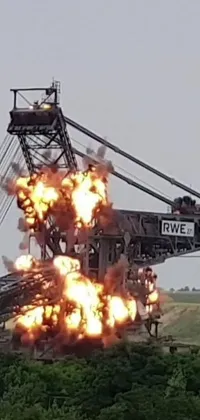 This live phone wallpaper features a towering crane with fiery explosions