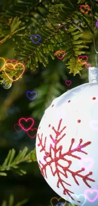 Add some holiday cheer to your phone with this charming Christmas ornament live wallpaper! The design features a stunning close-up shot of a sparkling ornament hanging from a tree branch, surrounded by glittering hearts in a whimsical digital art style