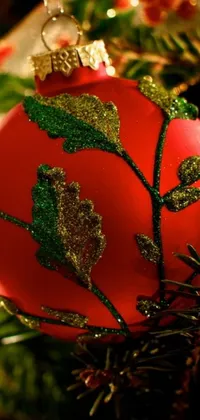 This stunning live wallpaper showcases a vibrant red Christmas ornament hanging beautifully from a green and gold tree