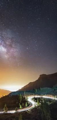 This mobile live wallpaper showcases a winding night road with a mesmerizing Milky Way backdrop featuring stars and planets