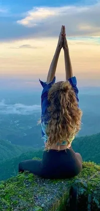 Looking for a serene and calming live wallpaper for your phone? Look no further than this breathtaking scene of a woman in a yoga pose atop a scenic mountain in Sri Lanka