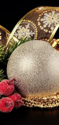 This stunning phone wallpaper captures a close-up of a Christmas ornament on a table adorned with silver and gold colors and bursts of red berries for a luxurious and lustrous appeal