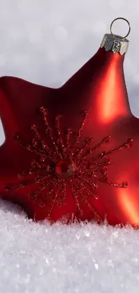 This enchanting phone live wallpaper features a vibrant red star ornament in a serene winter scene