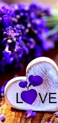This elegant live wallpaper displays a wooden heart with "love" written in script, amid a background of purple flowers and a captivating photo