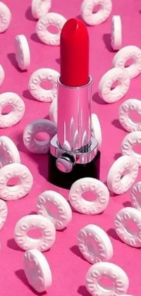 This live wallpaper for your phone features a bright red lipstick displayed on top of a tower of scrumptious donuts made of Swiss cheese wheels