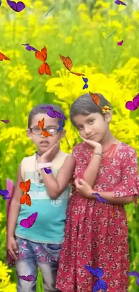 This live phone wallpaper features two adorable girls standing in a yellow flower field with a green garden visible through glasses in the background