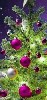 Capture the holiday spirit with this stunning live wallpaper for your phone! Featuring a beautifully decorated Christmas tree adorned in pink and silver ornaments, with gorgeous long violet and green trees in the background