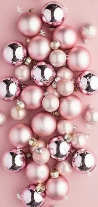 Get in the festive mood with this phone live wallpaper featuring a pile of pink Christmas ornaments on a soft pink background