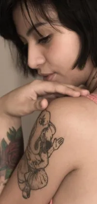 This phone live wallpaper features a woman with a tattoo on her arm looking over her shoulder