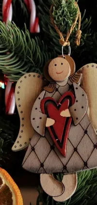 This live wallpaper for your phone offers a cozy scene: a wooden angel decoration adorns a Christmas tree in folk art style