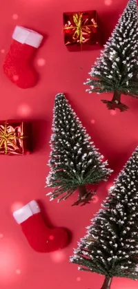 Get into the holiday spirit with this phone live wallpaper featuring a multitude of small Christmas trees sitting on a red surface, adorned with colorful ornaments and twinkling lights