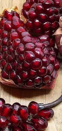 Elevate your phone with this charming live wallpaper featuring a pomegranate atop a wooden table