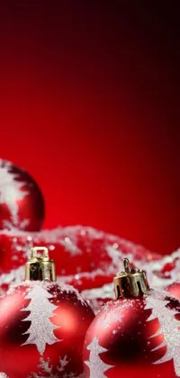 Get into the festive spirit with this stunning phone live wallpaper! Featuring a pile of red Christmas ornaments covered in snow, this wallpaper is perfect for adding a cozy touch to your mobile device