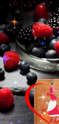 This live wallpaper features a stunning still life composition of fresh raspberries and blueberries arranged in a glass bowl on a black background