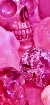 This live wallpaper showcases a group of intricately designed skulls on top of a rocky surface against a vibrant, pink slime backdrop