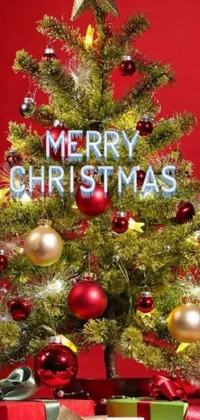 This phone live wallpaper features a cheerful Christmas tree with presents beneath it against a realistic red background