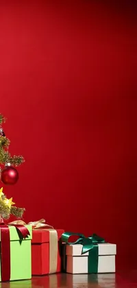 This Christmas-themed live wallpaper for phones features a beautifully decorated tree with colorful ornaments and sparkling lights, accompanied by wrapped presents in front of a red wall